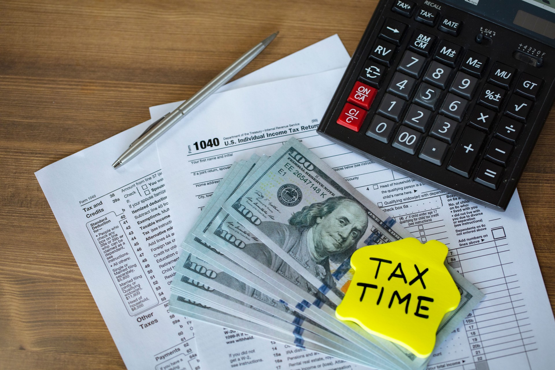 Tax time concepts. 1040 tax form on wooden table with calculator